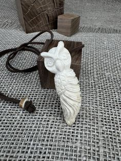 a white owl figurine sitting on top of a table next to a cord