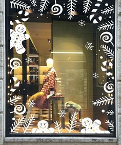 a window display with snowflakes and christmas decorations in the front, behind which is a mannequin's head