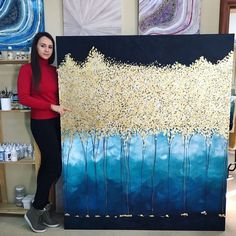 a woman standing next to a large painting