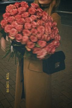 a woman is holding a large bouquet of roses