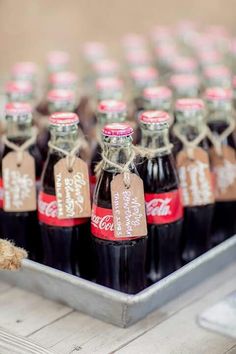 several bottles of coca - cola are sitting on a tray with tags tied to them