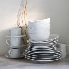 a stack of white plates and cups sitting next to each other