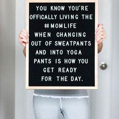 a woman holding up a sign that reads you know you're officially living the mom life when changing out of sweatpants and into yoga pants