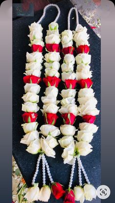 several red and white cupcakes are arranged on a black plate with pearls around them