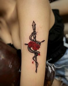 a woman with a rose and dagger tattoo on her arm