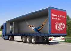 a large semi truck with a coca - cola advertisement on the side and a man laying in a hammock