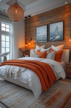 an orange and white bed in a bedroom with two pictures on the wall above it