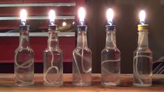 four bottles with candles in them sitting on a table