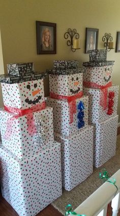 many wrapped presents are stacked on top of each other in front of a wall with pictures