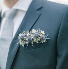 a man wearing a suit and tie with flowers on the lapel flower brooch