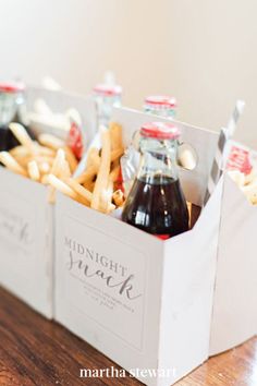 two bottles of soda and french fries in a white box on a wooden table top