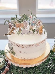 a white cake sitting on top of a wooden table covered in green plants and animals