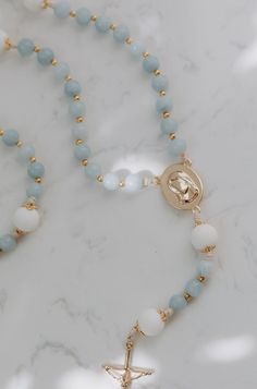 Inspired by the beloved apparitions of Our Lady of Medjugorje that still continue to this day. In her apparitions she revealed herself to be the Queen of Peace. The soft baby blues, and pure whites in this dreamy rosary brings out the truest most motherly, most Marian feel, just as the visionaries describe her as. With little gold accents and bead caps that resemble a crown, the details of this rosary exemplify the true queenship of Mary. Our Lady Queen of Peace, pray for us. Shop the entire Mat Dainty Christian Necklace, Mother Mary Bracelet, White Spiritual Rosary With Miraculous Medal, Spiritual White Rosary With Miraculous Medal, Our Lady Queen Of Peace, Rosary Drawing, Rosary Holder, Room Frames, Our Lady Of Medjugorje