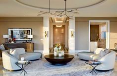 a living room filled with white furniture and a chandelier hanging from the ceiling