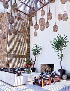 a living room filled with lots of furniture and hanging pots on the wall next to a fire place