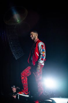 a man standing on top of a stage in front of a crowd wearing red and white pants