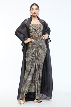 Black cape with crystal, zardozi, thread, sequin, stone embellishment. Paired with floral embellished corset and foil jersey draped skirt. - Aza Fashions Draped Skirt Pattern, Tulle Pants, Embellished Corset, Black Cape, Beige Jacket, Tarun Tahiliani, Stylish Blouse Design, Draped Skirt, Stylish Blouse