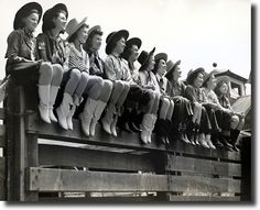 a group of women sitting on top of a wooden bench next to eachother