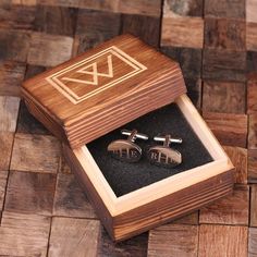 the cufflinks are in a wooden box with black sand and wood flooring