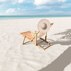 a chair with a hat on it sitting in the sand