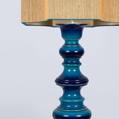 a blue table lamp with a beige shade on the top and bottom part of it