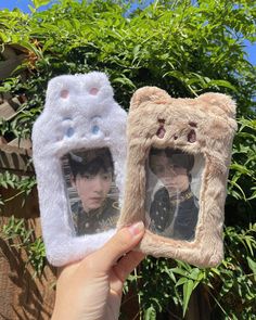 someone is holding up two pictures in their hands, one has a cat and the other has a bear