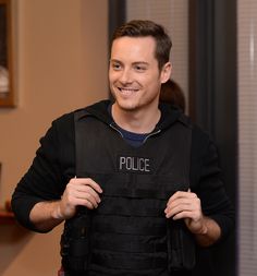 a police officer is smiling while holding onto his vest