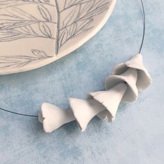 three pieces of white pottery sitting on top of a blue tablecloth next to a plate