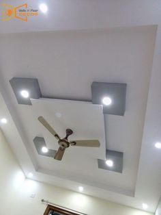 a ceiling with some lights on it and a fan hanging from the ceiling in front of them