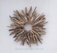 a wreath made out of driftwood is mounted on the side of a white wall