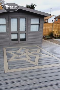 a wooden deck with an arrow design painted on the floor next to a small building