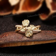 a close up of a gold ring on top of a piece of wood with flowers