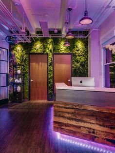 an office with wooden floors and purple lighting on the walls is lit up by lights