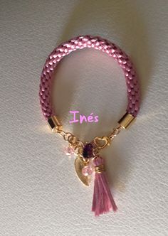 a pink bracelet with a heart charm and a tassel on the end of it