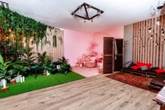 a living room filled with lots of green plants and decor on top of wooden floors