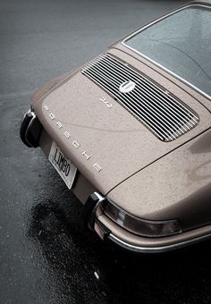 an old car is parked in the rain