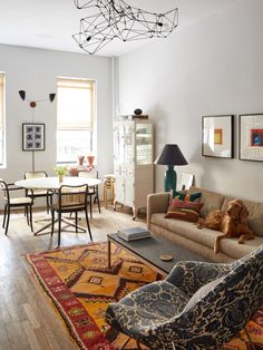 a living room filled with furniture and a dog on top of a rug in front of a window