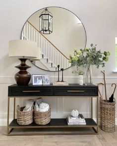 a console table with a mirror and vase on it in front of a stair case