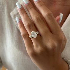 a woman's hand with a ring on it and a white manicured nail polish