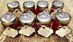 six jars of jam sitting on top of a lace tablecloth with tags around them