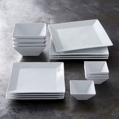 a bunch of white dishes sitting on top of a table