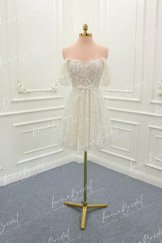 a white dress on a mannequin stand in front of a wall and floor