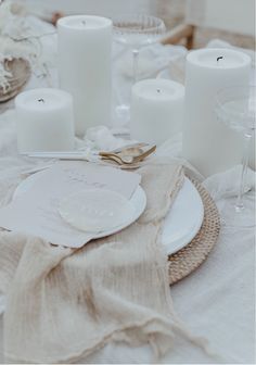 a table set with candles, plates and napkins