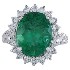 an oval emerald and diamond ring with white diamonds around it, set in 18k white gold