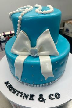 a blue cake with white bows and pearls