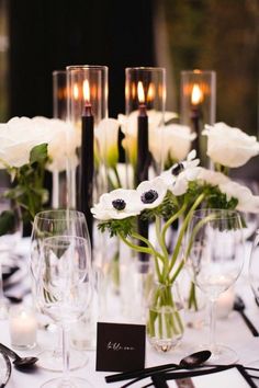 a table with white flowers and candles on it is set for an elegant dinner party