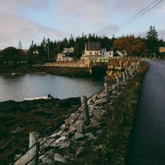 a road next to a body of water with houses in the background