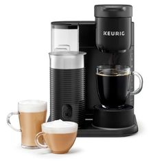 the keurig coffee maker and two cups are next to each other on a white surface