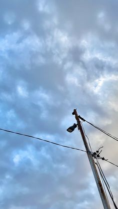 an old telephone pole and wires against a cloudy sky