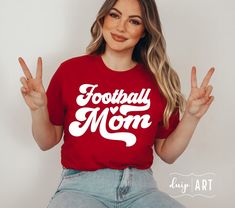 a woman wearing a red football mom t - shirt with the words football mom written on it